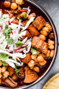 a bowl filled with meat and vegetables next to some tortilla chips on the side