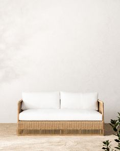 a white couch sitting on top of a wooden floor next to a potted plant