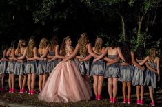 a group of young women standing next to each other in front of trees and bushes