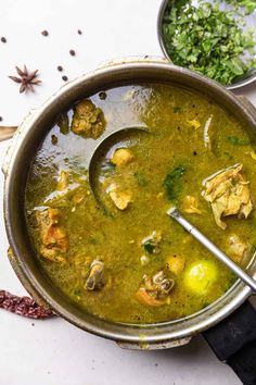 a pot filled with green soup on top of a white counter next to other dishes