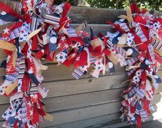 two red, white and blue wreaths hanging from a wooden fence