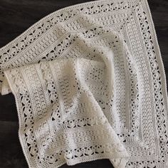 two white crocheted afghans sitting on top of a wooden floor