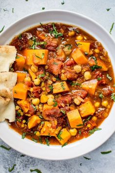 a white bowl filled with stew and pita bread