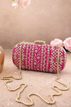 "Put together the perfect wedding look with our Mirai Embroidered clutch. This bag effortlessly delivers the Indian festive look. The luxe gold embroidery is a visual delight to the eyes. The gold tassels and the gold scallop lace add on to the grandeur of the bag. It's the perfect accessory for the bride to be who will be the center of attention.   Color: Pink with gold embroidery Dimensions (LxB): 8\"x4\" Handle length: 47\" Handle drop: 23\" Material: Embroidered poly silk, suede lining, golden metal clutch frame, golden metal sling. Features: metal lock closure, detachable metal sling." Luxury Gold Embroidered Clutch For Wedding, Luxury Wedding Clutch With Gold Embroidery, Embroidered Rectangular Evening Bag For Reception, Pink Bags For Evening And Festivals, Rectangular Gold Embroidered Evening Bag For Receptions, Traditional Pink Shoulder Bag For Evening, Festive Rectangular Clutch With Gold Embroidery, Festive Embroidered Clutch Evening Bag, Luxury Embroidered Festive Bag