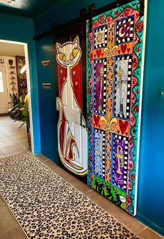 two colorful doors with cats painted on them in front of a blue wall and leopard print rug