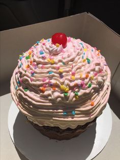 there is a large cake with pink frosting and sprinkles on it