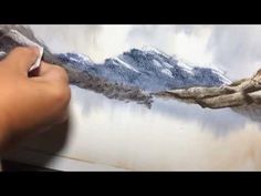 someone is painting a mountain scene with watercolors