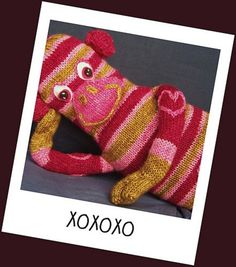 a pink and yellow knitted animal laying on top of a gray surface with the words oxox written below it