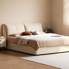 a white bed sitting next to a window on top of a wooden floor in a bedroom