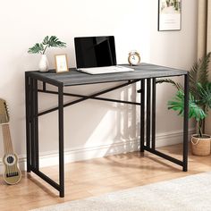 a computer desk with a laptop on top of it next to a potted plant