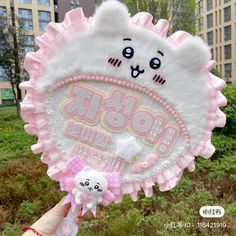 a person holding up a pink and white stuffed animal