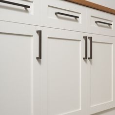 a kitchen with white cabinets and black handles