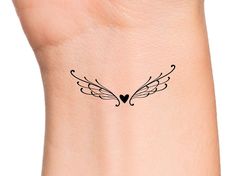 a small tattoo on the wrist of a woman's arm with an angel wing and heart