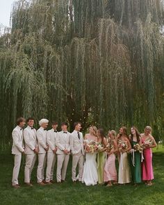 a group of people standing next to each other in front of a large willow tree