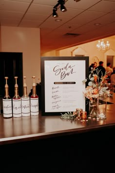 a menu sitting on top of a wooden table next to liquor bottles and flowers in vases