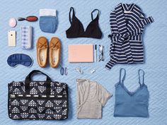 the contents of a woman's travel bag laid out on a blue blanket with shoes, bras and other items