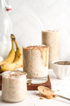 two glasses filled with oatmeal sitting on top of a table next to bananas