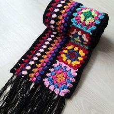 a multicolored crocheted scarf laying on top of a white table