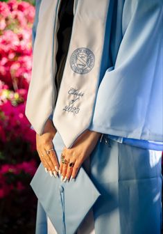 a woman wearing a blue graduation gown and holding her hand in her pocket