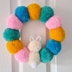 a multicolored wreath with a bunny head hanging on the side of a door