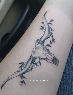 a lizard tattoo on the leg of a person's leg, with flowers growing out of it