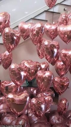 many shiny heart shaped balloons hanging from the ceiling