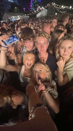 a group of people standing in front of a crowd holding up their cell phones to take pictures