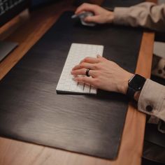 a person typing on a computer keyboard with their hand resting on the mouse pad while sitting at a desk