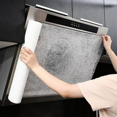 a woman is holding up a large roll of paper to the oven door and it's handle