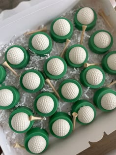 green and white cupcakes in a box with toothpicks on them are ready to be eaten