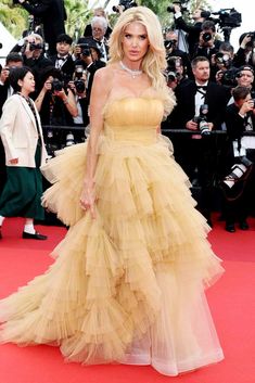 a woman in a yellow dress standing on a red carpet