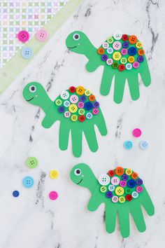 two paper turtles made out of buttons on a marble surface with other crafting supplies