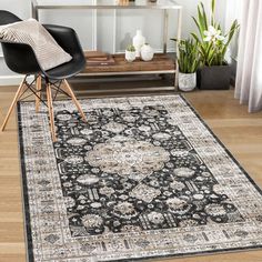 a black and white area rug with an ornate design on the center, in front of a