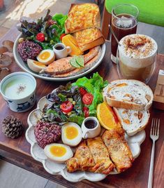 two plates filled with food sitting on top of a wooden table next to cups and saucers