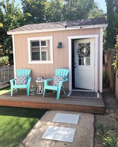 two blue chairs sitting on top of a wooden deck in front of a small house