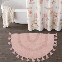 a bath tub sitting next to a pink rug on top of a wooden floor