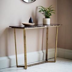 a table with a plant on it and a mirror in the corner behind it that is next to a wall