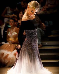 a woman in a black and white dress standing on a runway