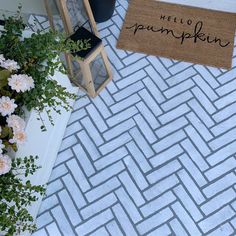 a welcome mat with the words hello pumpkin on it next to flowers and a doormat