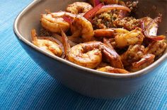 a bowl filled with shrimp and vegetables on top of a blue table cloth next to a fork