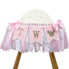 a pink and gold minnie mouse 1st birthday party banner on a wooden tripod stand