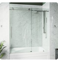 a bath tub sitting under a window next to a plant in a white tiled bathroom