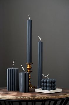 three tall candles sitting on top of a table next to some black and white boxes