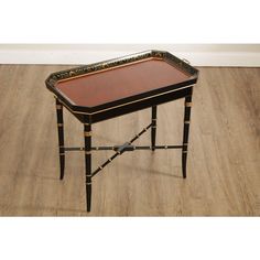 a black and gold tray table on wooden floor with white wall in the back ground