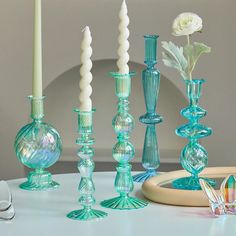 there are many different colored glass vases on the table with one white rose in it