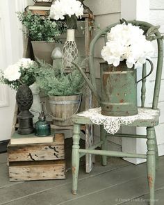 an old chair sitting on the porch next to some potted plants and other items