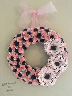 a wreath with pink and white flowers hanging on the wall