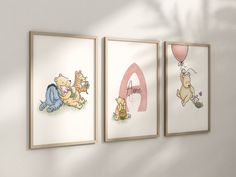 three winnie the pooh prints hanging on a wall next to each other with balloons