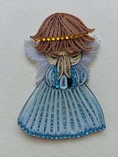 a paper sculpture of a girl wearing a blue dress with gold beads on her head