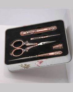 three pairs of scissors in a box with floral designs on the sides and pink handles